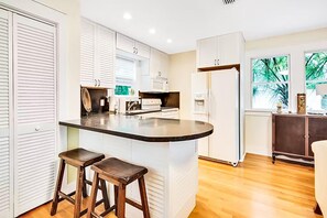 Enjoy cooking in this well-equipped kitchen with a central island and stools, featuring a stove, microwave, and refrigerator.