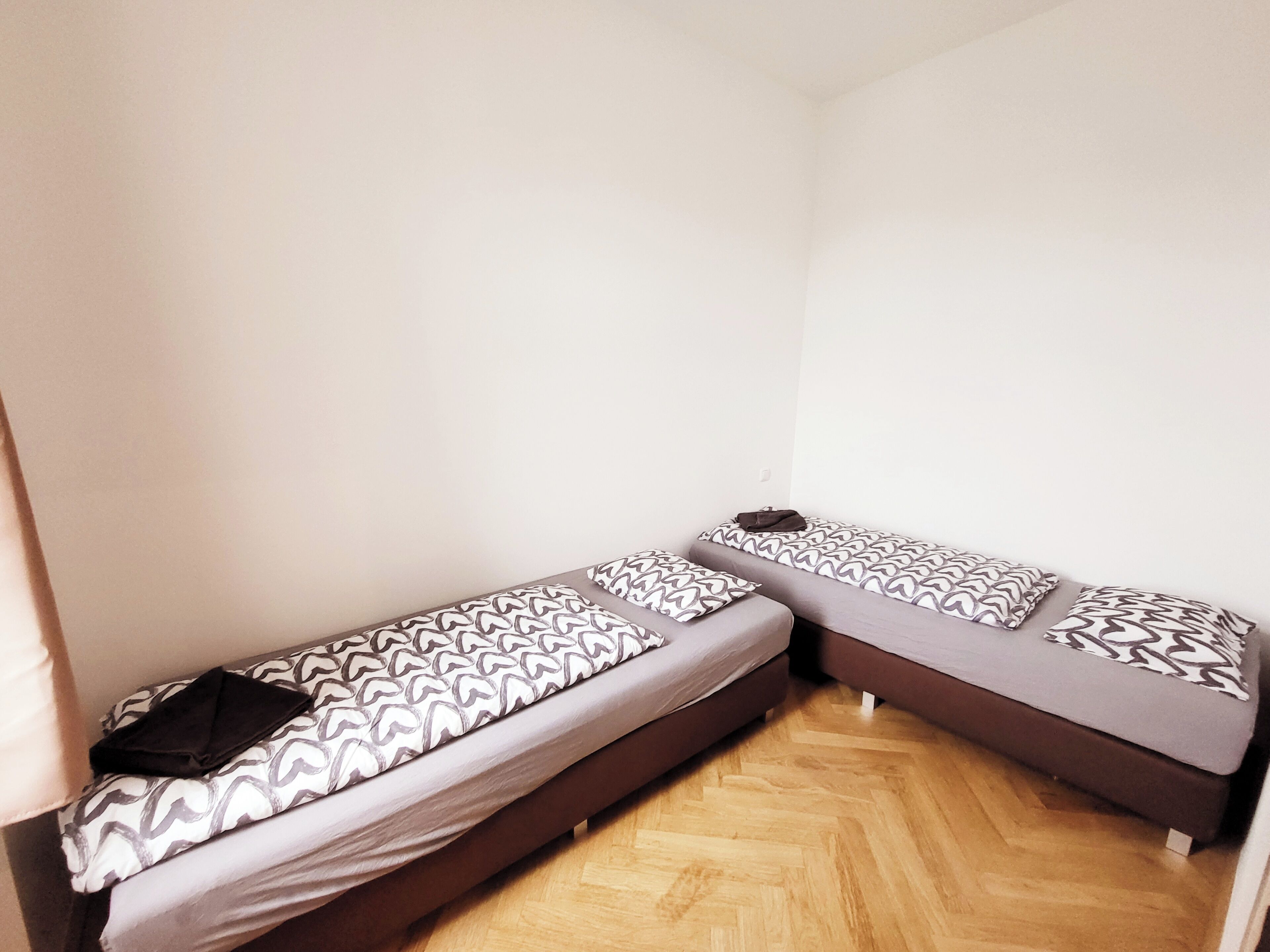 A room with two single beds, each with patterned bedding and a pillow.