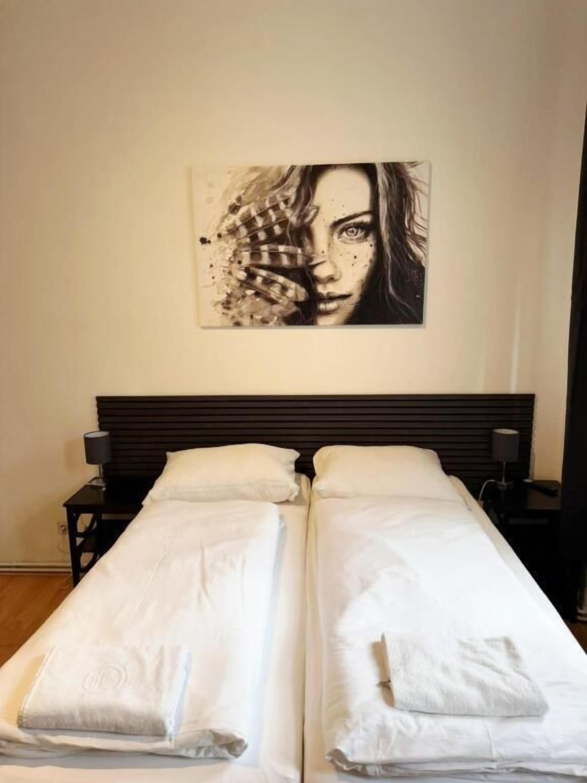 A double bed with white linens, a headboard, and a wall-mounted artwork.