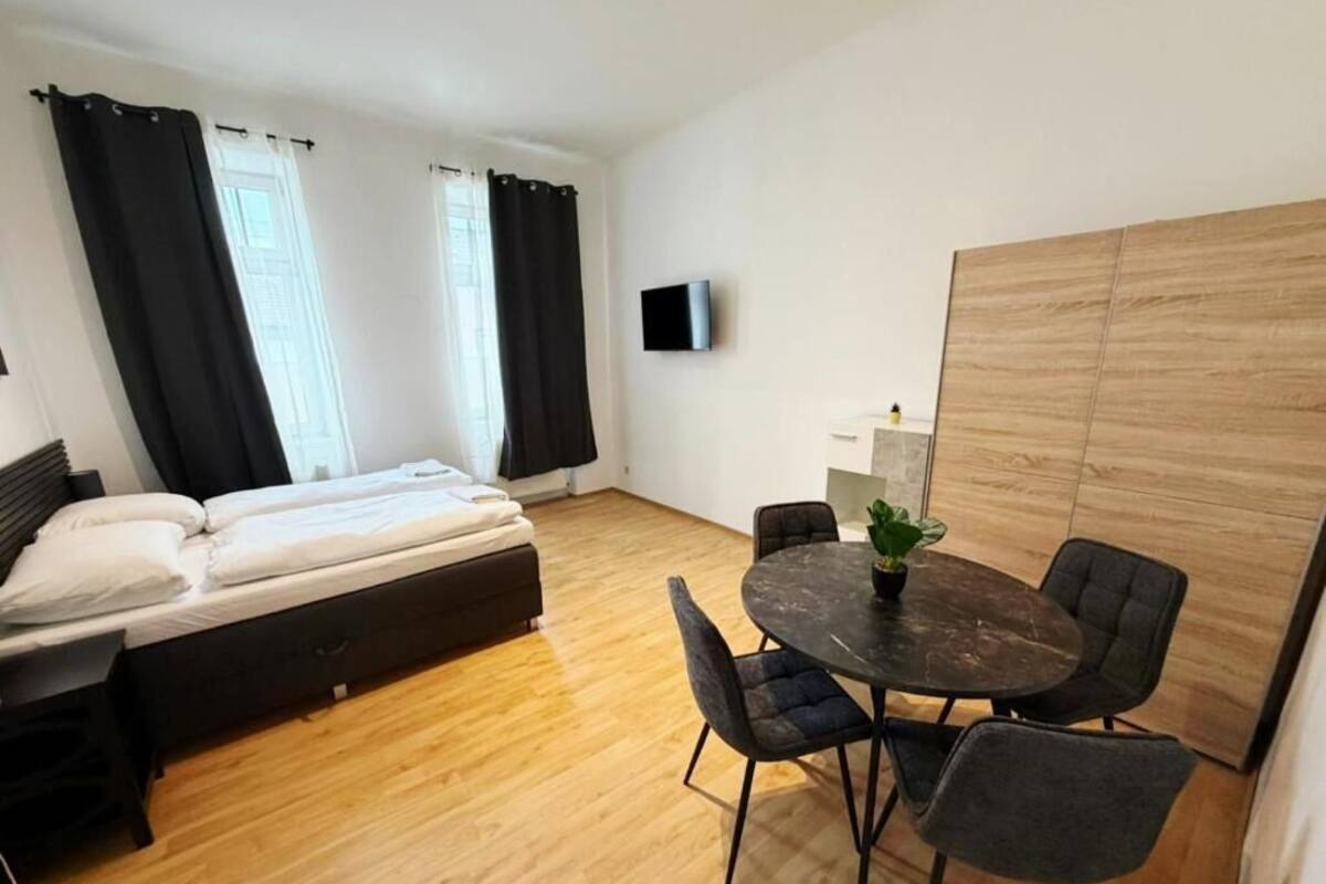 Een kamer met een bed, een ronde tafel met stoelen, een televisie aan de muur en een houten scheidingswand.