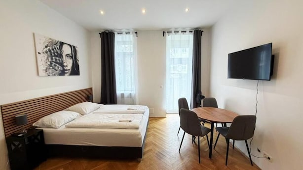 Une chambre d’hôtel avec un lit, une télévision, une table à manger avec des chaises et un tableau au mur.