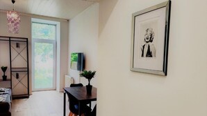 Un salon moderne avec un plancher en bois, une table à manger avec des chaises, un canapé noir, une petite plante et un tableau encadré accroché au mur.