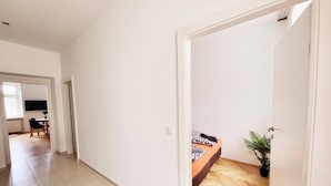 Un couloir avec un lit et une plante en pot dans une pièce.