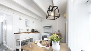 Una cucina con mobili bianchi, un piano di lavoro in legno, una lampada a sospensione e un fornello bianco.