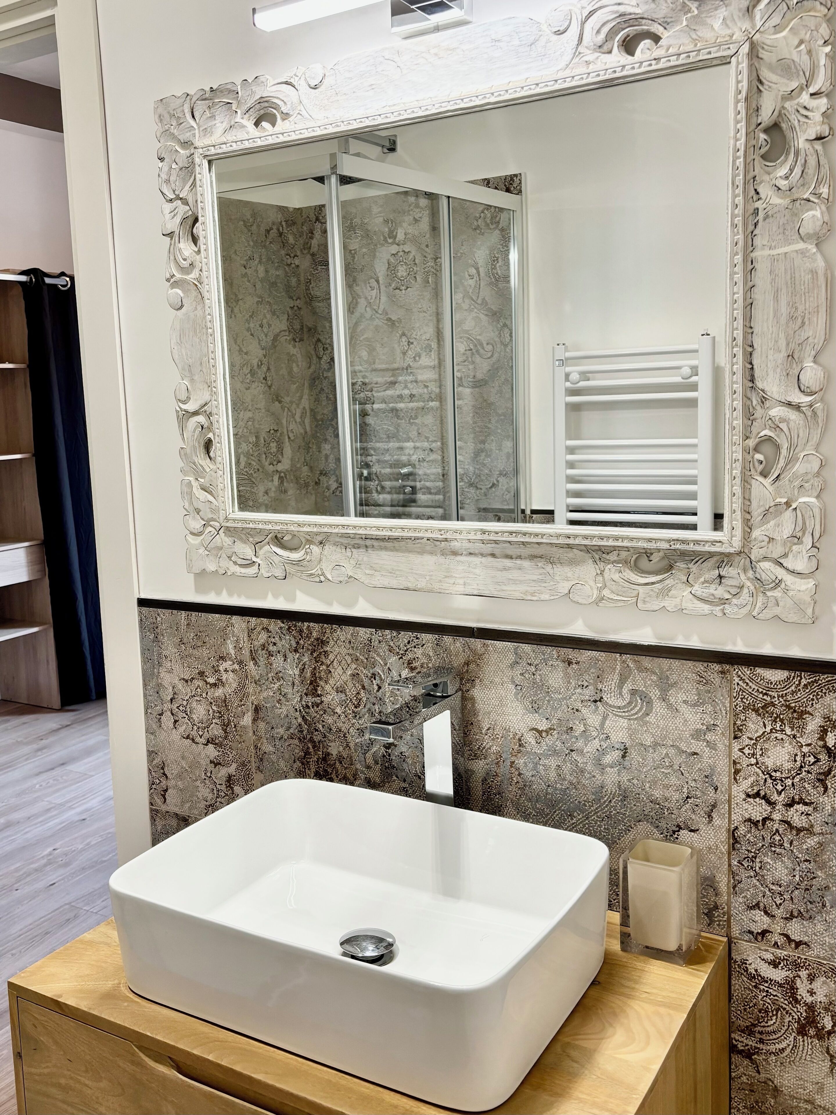 A bathroom with a large mirror, a white sink, and a towel rack.