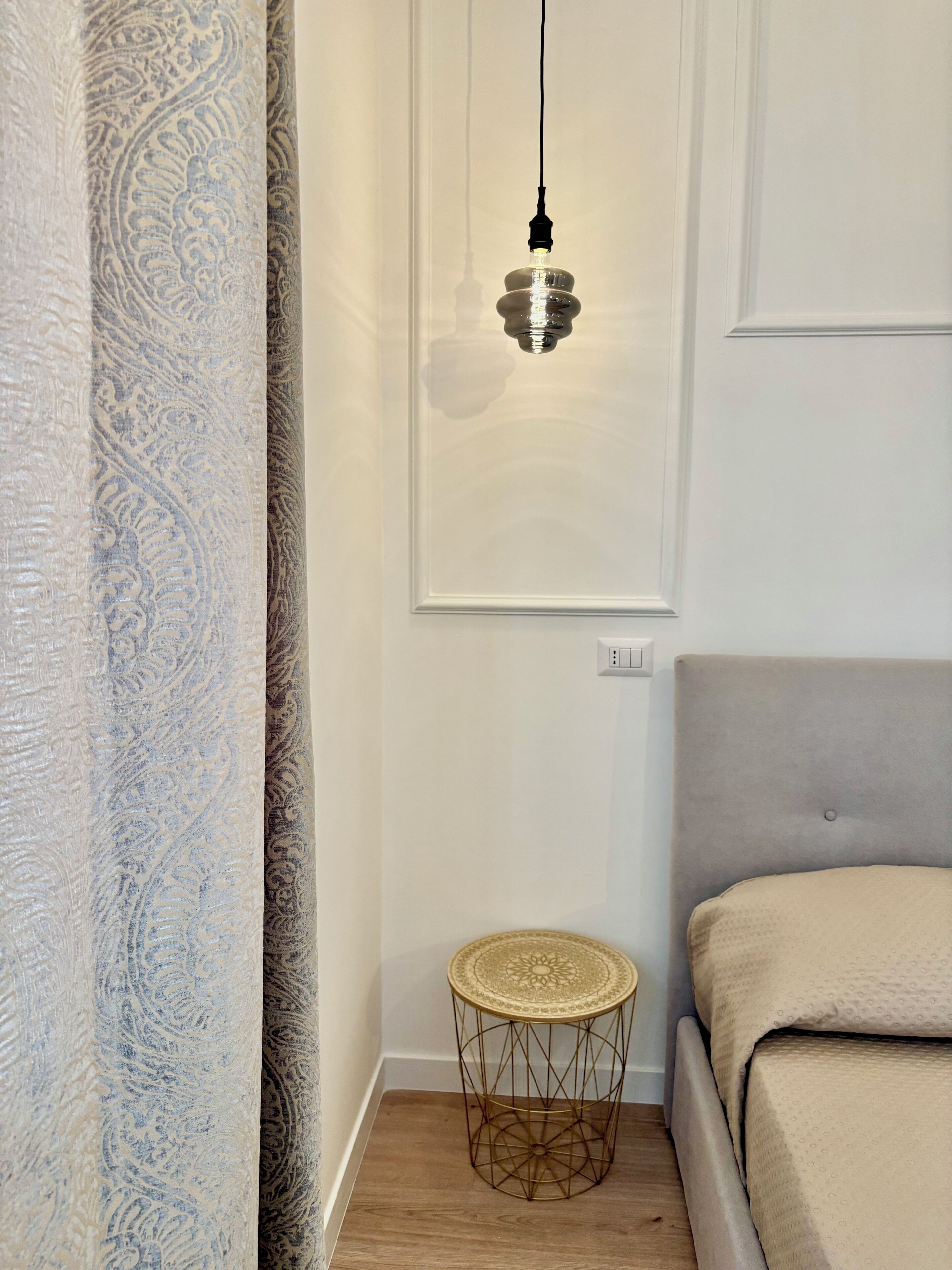 Une chambre à coucher avec un lit, une table de chevet et un luminaire suspendu.