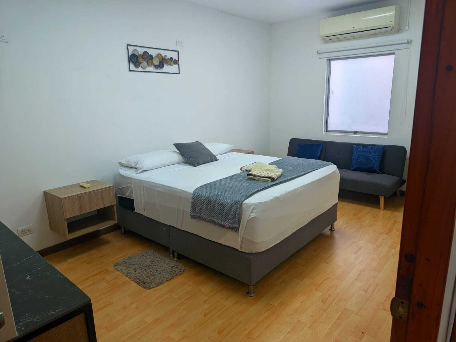 Un dormitorio con cama, mesita de noche y sofá.