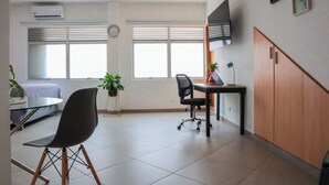 A modern office space with a desk, chair, and potted plants. - Manila Apartaestudios  (Medellín)