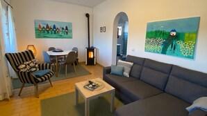 Ein Wohnzimmer mit Sofa, Sessel, Esstisch und Kamin.