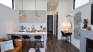 A modern kitchen with pendant lights, a central island, and a dining area with a fireplace. - Xhale Resort and Spa (Idaho Falls)