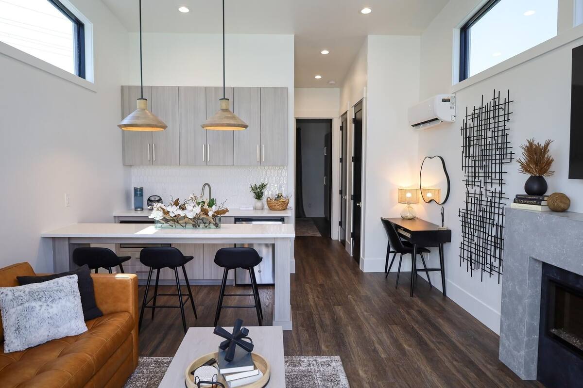 Una cocina moderna con lámparas colgantes, una isla central y un comedor con chimenea.