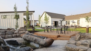A patio area with a wooden deck, outdoor seating, and a small water feature. - Xhale Resort and Spa (Idaho Falls)