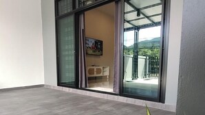 A modern living room with a large sliding glass door leading to a balcony. - Hillview Terrace (Hat Yai)