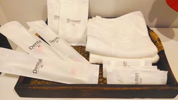 A tray with various toiletries including dental kits, a shower cap, and cotton buds. - Hillview Terrace (Hat Yai)
