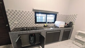 A modern kitchen with a checkered backsplash, a window above the sink, and a built-in dishwasher. - Hillview Terrace (Hat Yai)