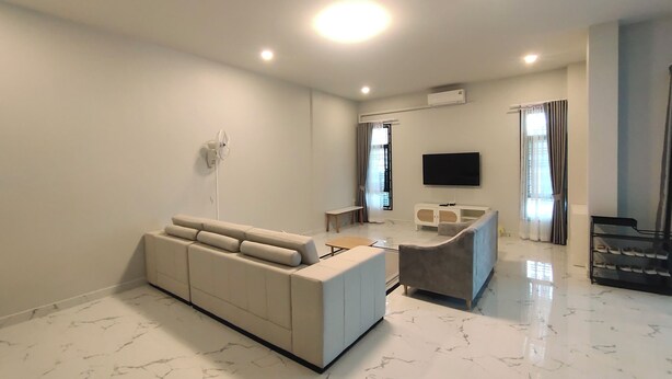 A modern living room with a sofa, a coffee table, a TV, and a shoe rack. - Hillview Terrace (Hat Yai)
