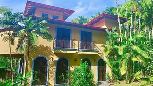Un edificio de dos pisos con techo rojo, varios balcones y ventanas arqueadas.