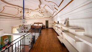 Ein Zimmer mit Holzboden, einer Treppe, einem Chandelier und einer weißen Wand mit Regalen.