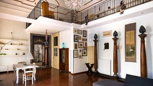 Ein großzügiger Wohnbereich mit hoher Decke, Holzboden, einer Treppe und einem Balkon.