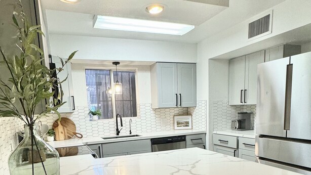 Una cocina moderna con encimera de mármol, electrodomésticos de acero inoxidable y una isla grande con taburetes de bar.