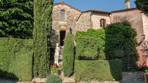 A historic stone building with a central doorway, flanked by neatly trimmed hedges and a statue. - Charming 4-bedroom villa in San Gimignano with private pool, hot tub and gym. (Toscana)