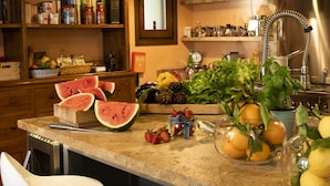 A kitchen counter with various fruits and vegetables, a sink, and a stove. - Charming 4-bedroom villa in San Gimignano with private pool, hot tub and gym. (Toscana)