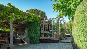 A rustic garden with a wooden structure, a hammock, and a greenhouse. - Charming 4-bedroom villa in San Gimignano with private pool, hot tub and gym. (Toscana)