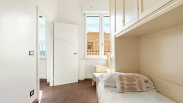 A bedroom with a bed, a chair, and a window with a view of buildings.