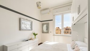 Une chambre à coucher moderne avec un lit, une commode et une grande fenêtre.