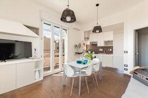 A modern kitchen with white cabinets, a dining table with chairs, and pendant lights. - Beach Apartment (Rome)