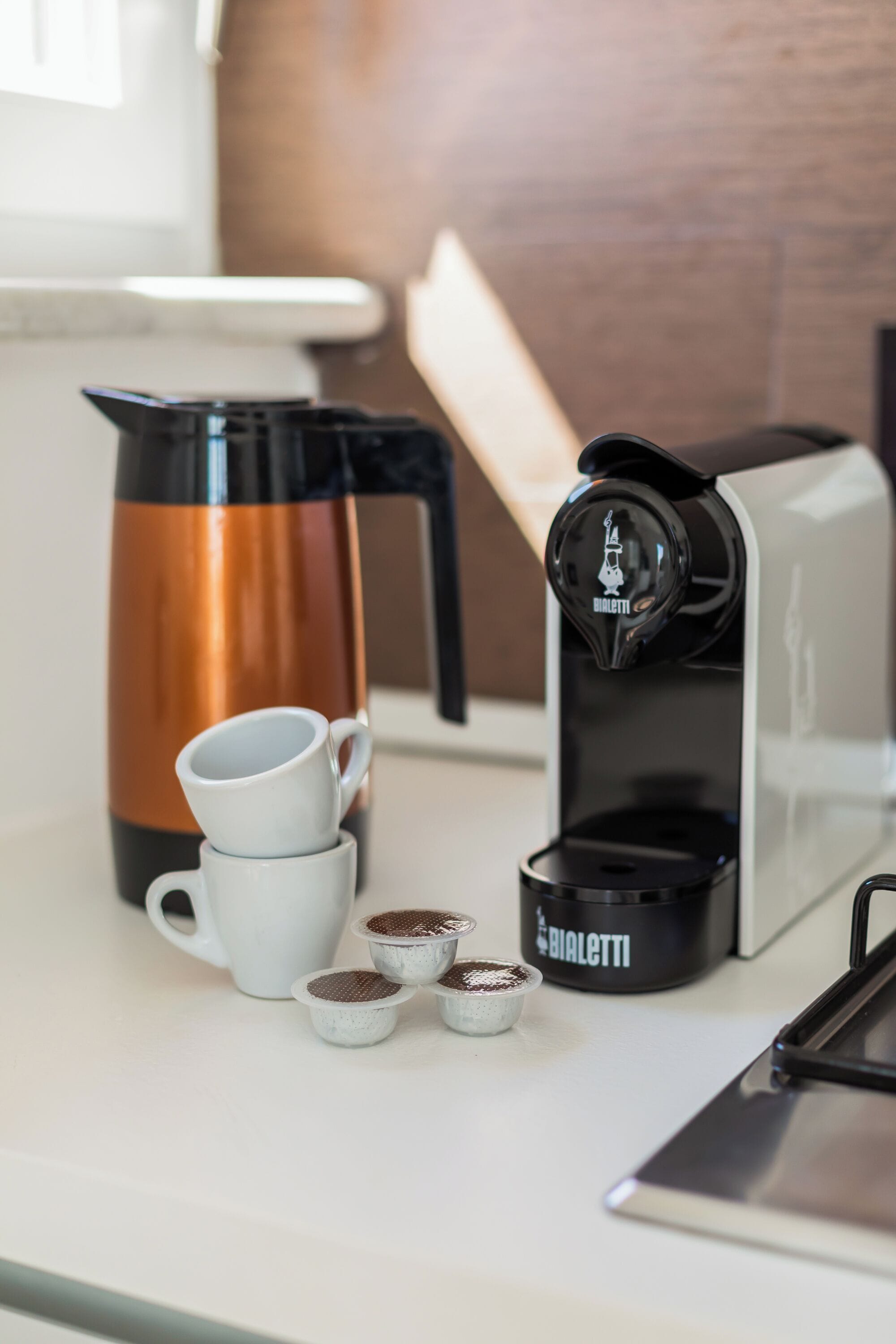 A coffee maker, a coffee pot, and coffee cups on a kitchen counter.