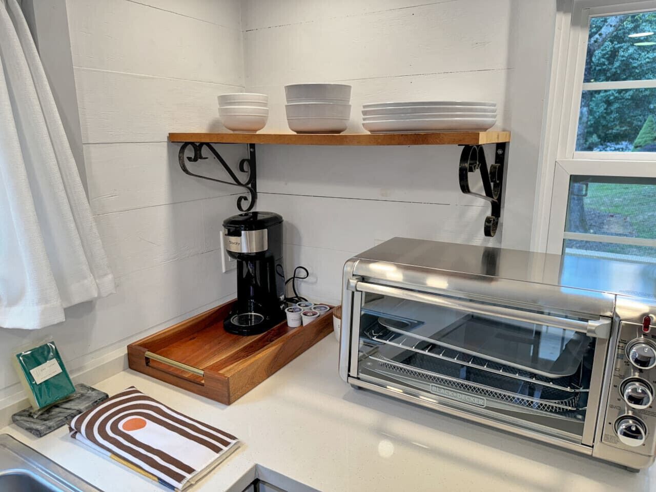 A kitchen with a toaster oven, a coffee maker, and a shelf with bowls.