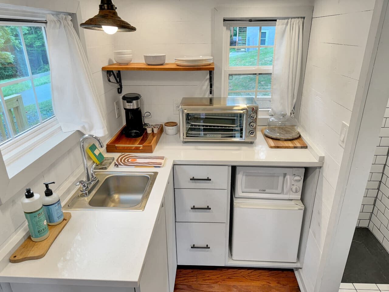 Una cocina compacta con pileta, tostadora, microondas y heladera pequeña.