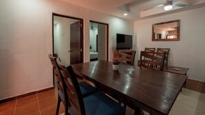 Un coin repas comprenant une table en bois, des chaises, un ventilateur de plafond et un téléviseur.