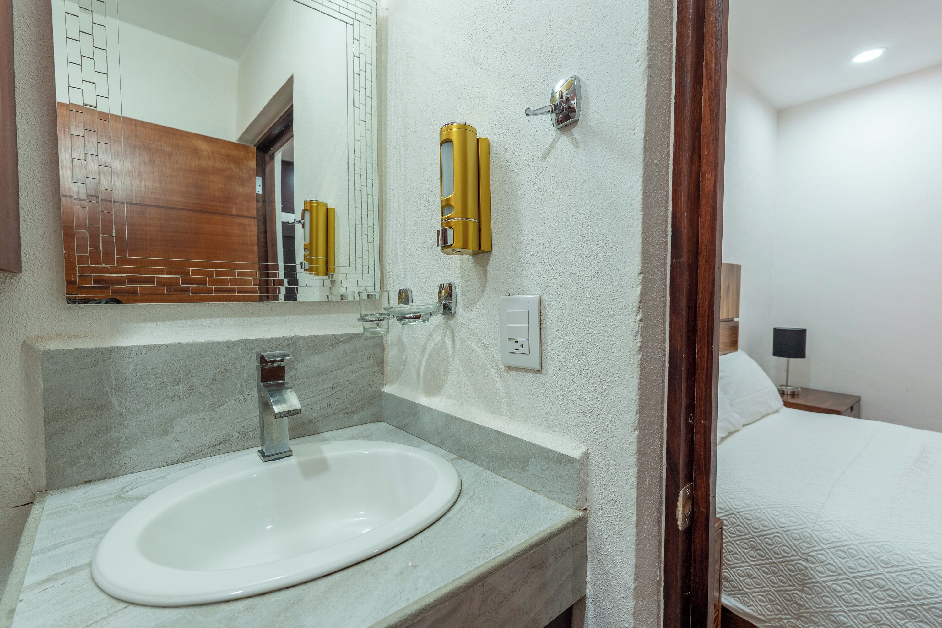 Une salle de bain équipée d’un lavabo, d’un miroir et d’un distributeur de serviettes.