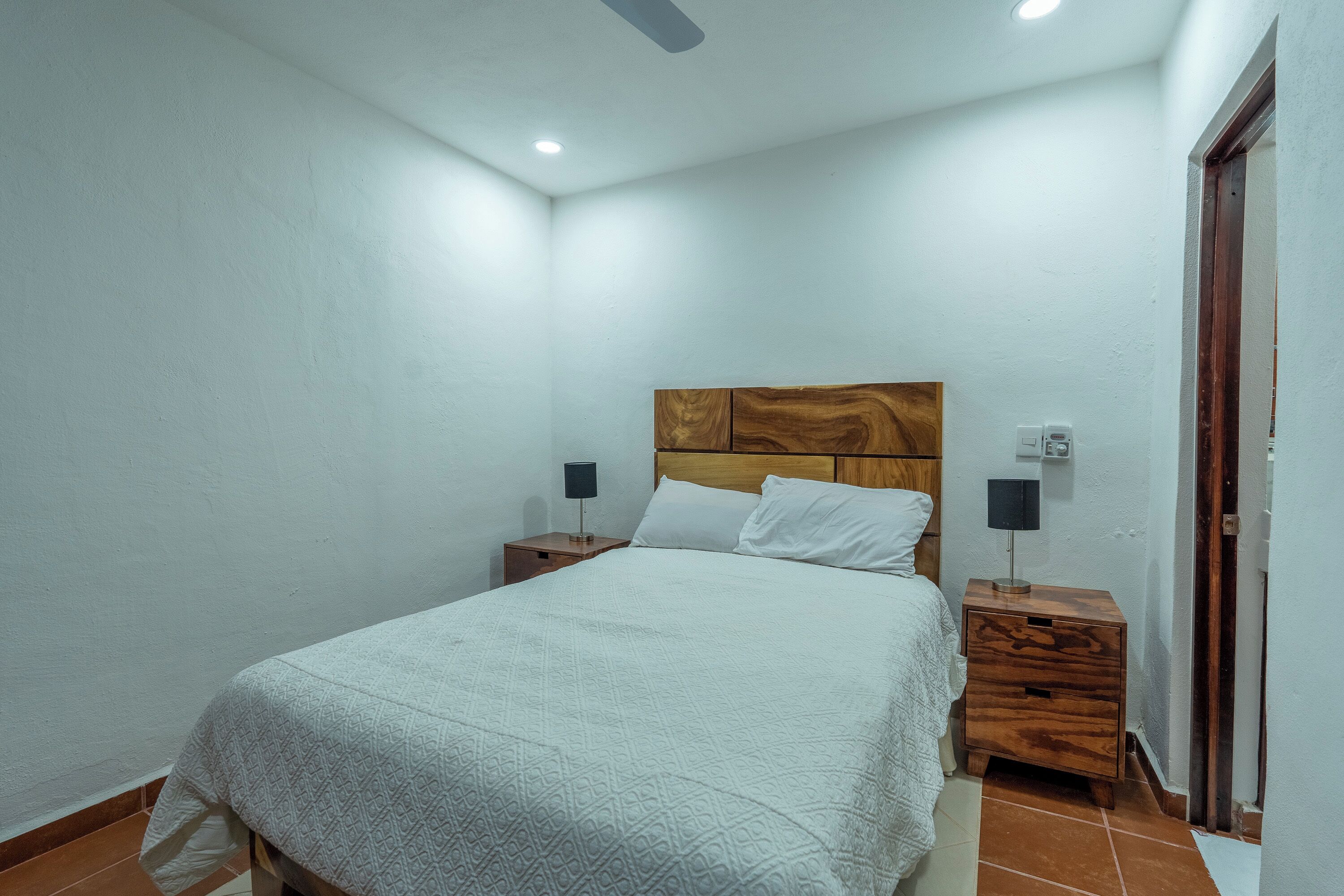 A bedroom with a bed, nightstands, and a wooden headboard.