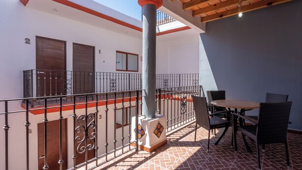 Un balcon avec un sol carrelé, une table avec des chaises et une rambarde.