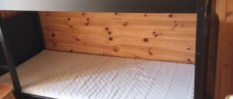 A bunk bed with a wooden headboard and mattress.