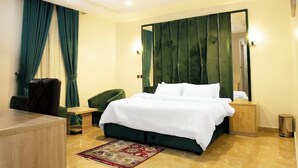 A modern hotel room with a large bed, a desk, and a chair. - EdisPremier Hotel & Suites (Port Harcourt)