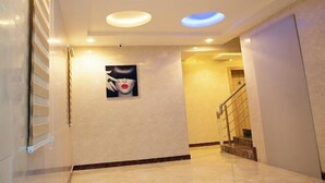A hallway with a marble floor, recessed ceiling lights, a staircase, and a wall-mounted artwork. - EdisPremier Hotel & Suites (Port Harcourt)