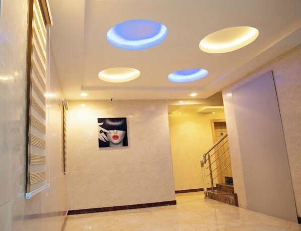 A hallway with a marble floor, recessed ceiling lights, a staircase, and a wall-mounted artwork. - EdisPremier Hotel & Suites (Port Harcourt)
