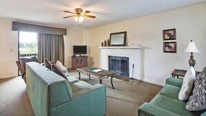 A living room with a sofa, a coffee table, a fireplace, and a television. - Crossville Calling: Fairways, Forests & Fresh Air (Crossville)
