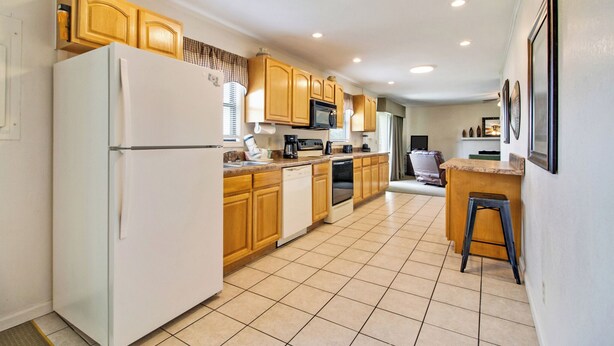 A modern kitchen with wooden cabinets, a white refrigerator, a microwave, and a dishwasher. - Crossville Calling: Fairways, Forests & Fresh Air (Crossville)