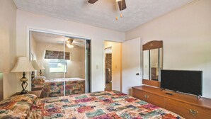 Ein Schlafzimmer mit Bett, Kommode, Fernseher und Deckenventilator.