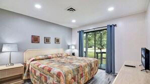 Une chambre à coucher avec un lit, des lampes de chevet, un bureau et un téléviseur.