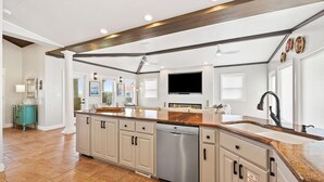 Una cocina moderna con una isla central, lavavajillas integrado y un amplio ventanal.