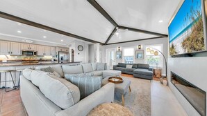 Amplia sala de estar con un sofá modular grande, una chimenea y una cocina al fondo.