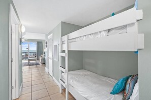 Une chambre avec des lits superposés, une vue sur l’extérieur et un sol carrelé.