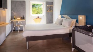 A bedroom with a bed, bedside table, and a desk with a chair. - Ibis Budget Bourg-En-Bresse (Bourg-en-Bresse)