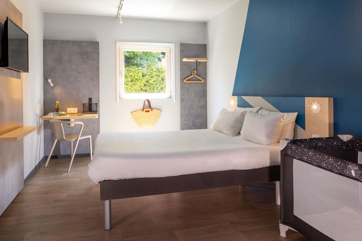 A bedroom with a bed, bedside table, and a desk with a chair.
